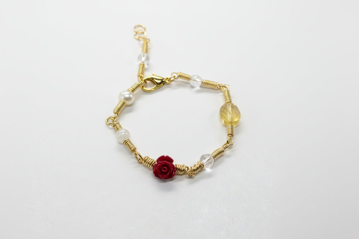 Copper gold plated bracelet with red flower charm on a gray background