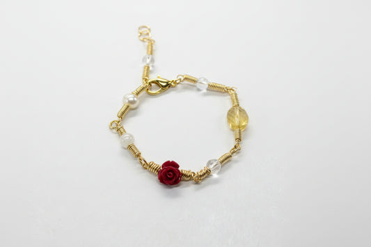 Copper gold plated bracelet with red flower charm on a gray background
