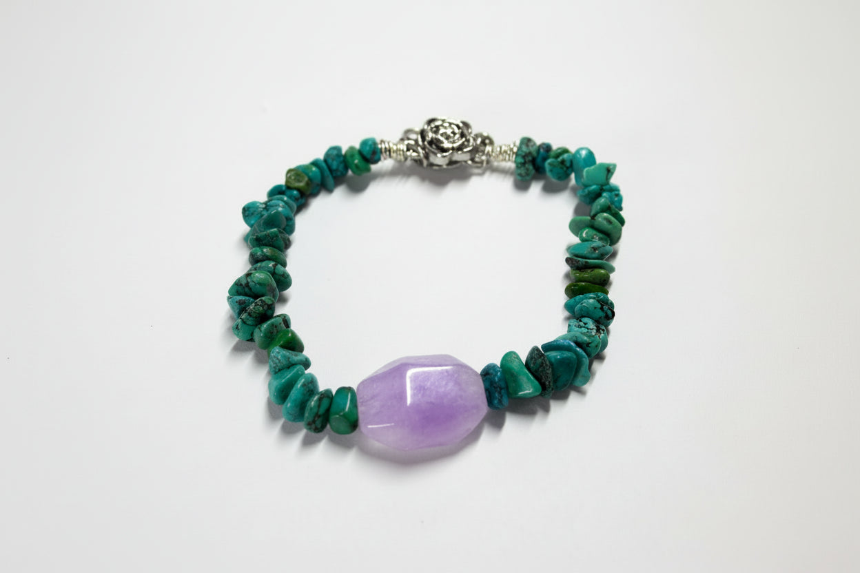 Bracelet with green beads and a purple stone on a white background
