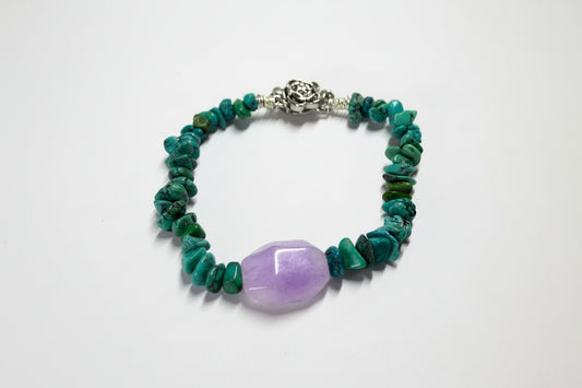 Bracelet with green beads and a purple stone on a white background